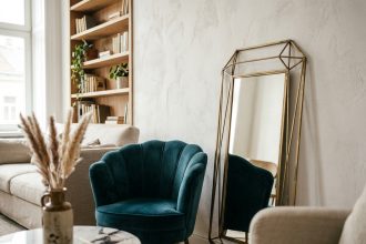 Coin salon avec miroir géométrique en laiton et fauteuil en velours style art déco intégré dans un intérieur moderne