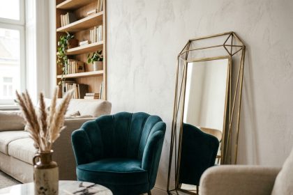 Coin salon avec miroir géométrique en laiton et fauteuil en velours style art déco intégré dans un intérieur moderne